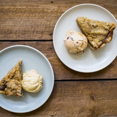 Two plates with an apple pie slice on each of them served a la mode