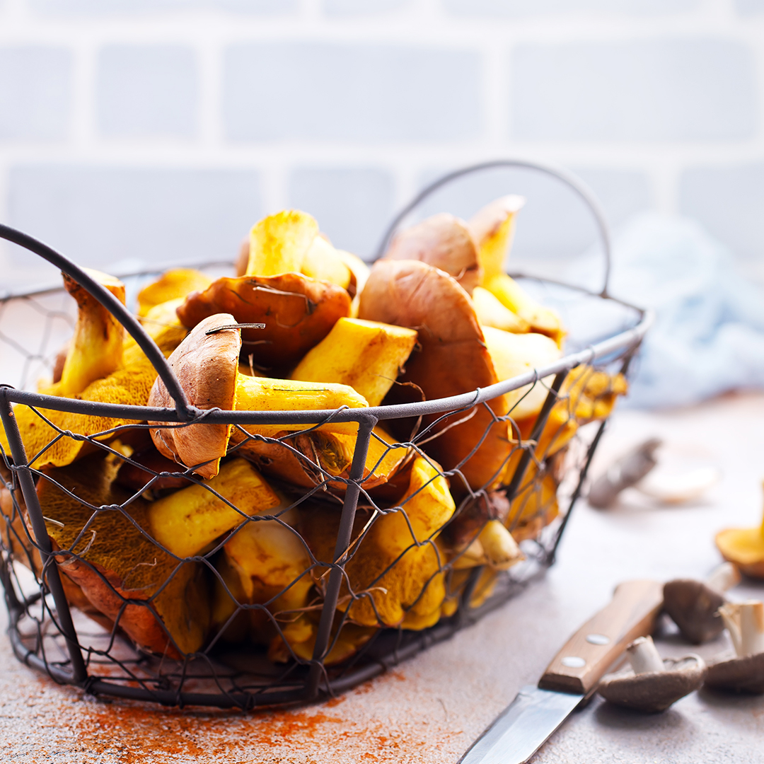 A metal basket of mushrooms on a kitchen counter