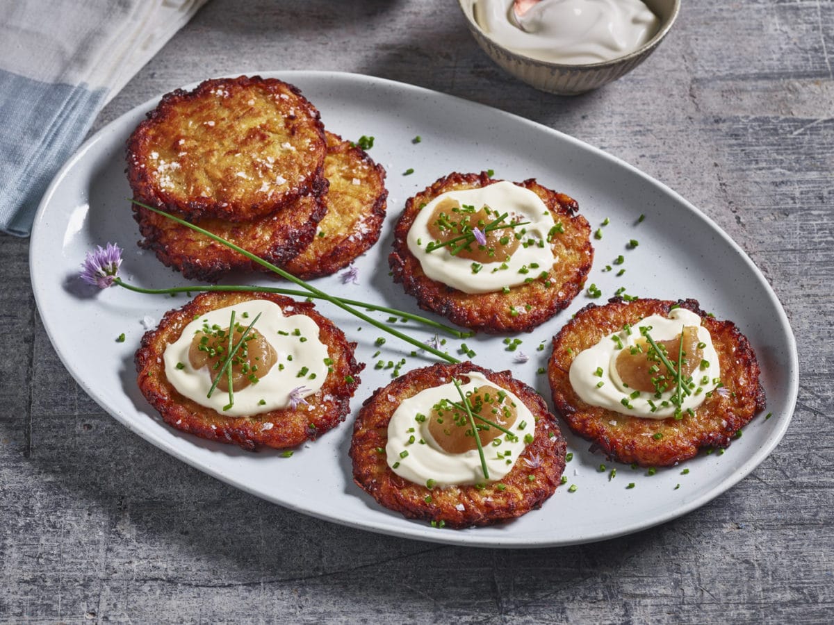 A plate of latkes dressed with sour cream, apple sauce and herbs