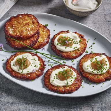 A plate of latkes dressed with sour cream, apple sauce and herbs