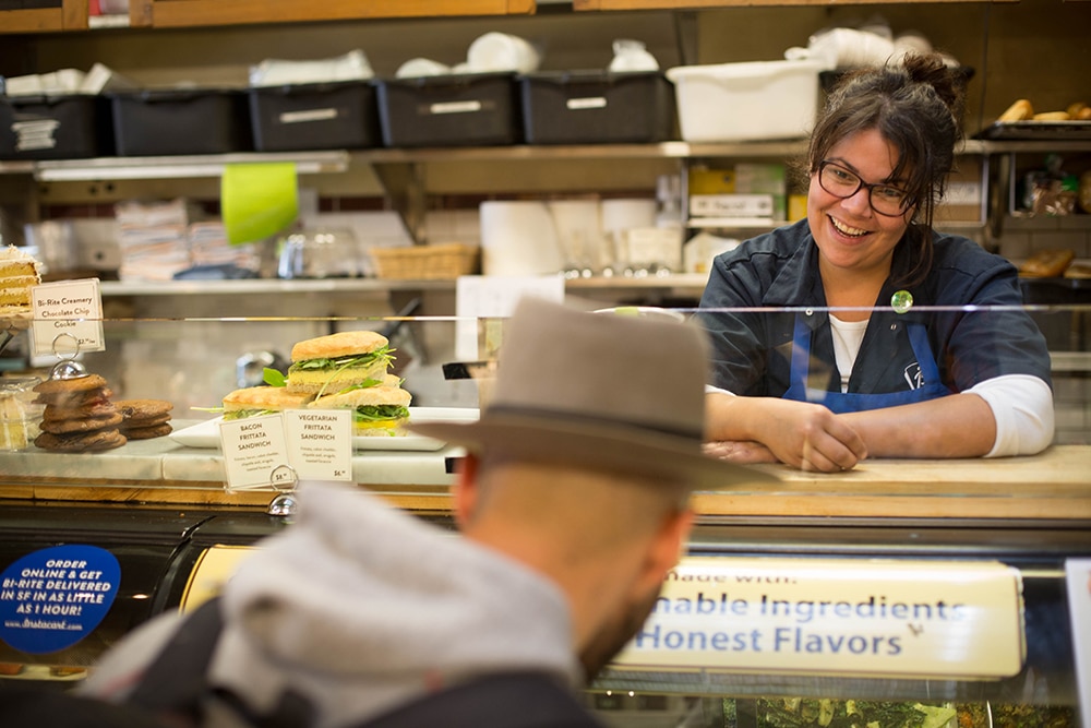 Team member standing behind the deli talking to a guest in front