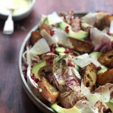 Close up of a bowl of salad with dressing with a spoon in it off to the side