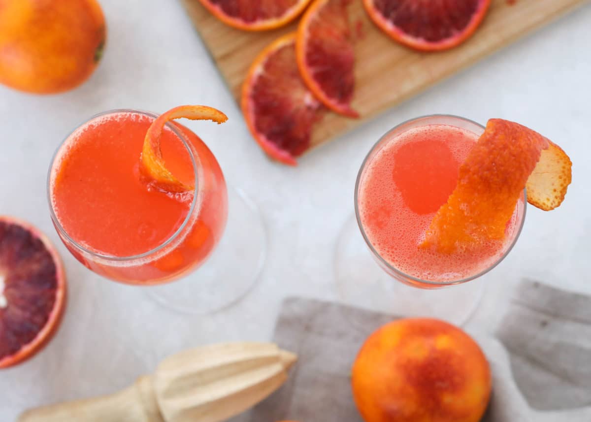 Two cocktails shot from above surrounded by juicing tools and citrus slices