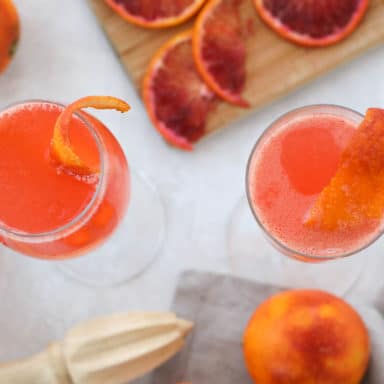 Two cocktails shot from above surrounded by juicing tools and citrus slices