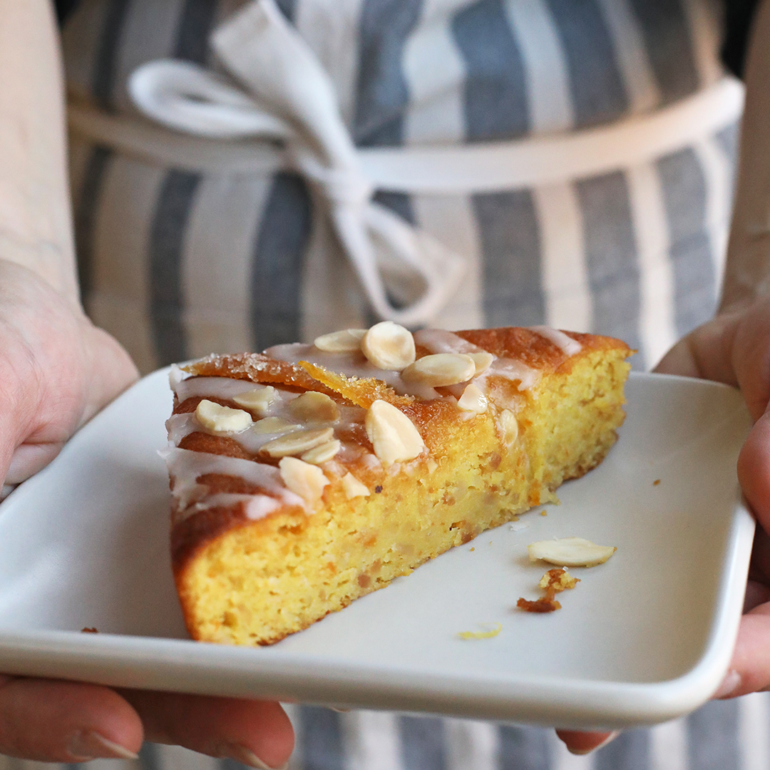 A person serving a slice of cake on a square plate