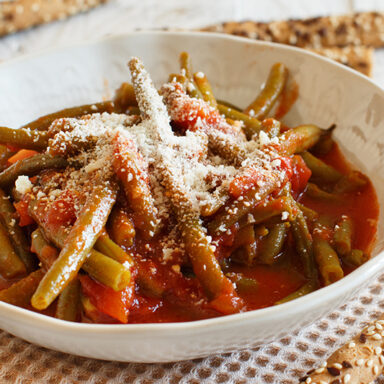Beans in a tomato sauce topped with parmesan on a table cloth