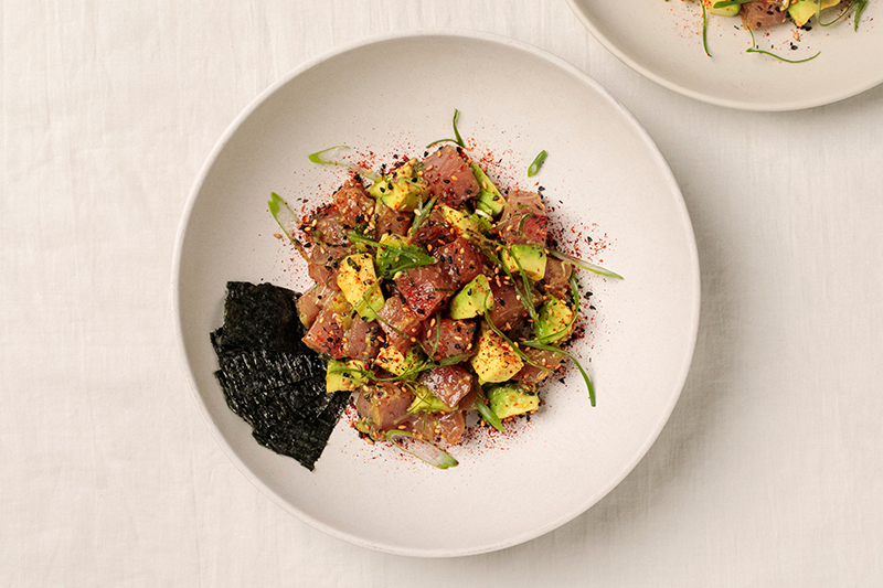 A bowl of poke with strips of seaweed