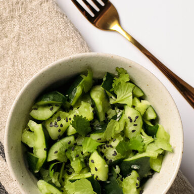 Bowl of smashed cucumbers with napkin and fork