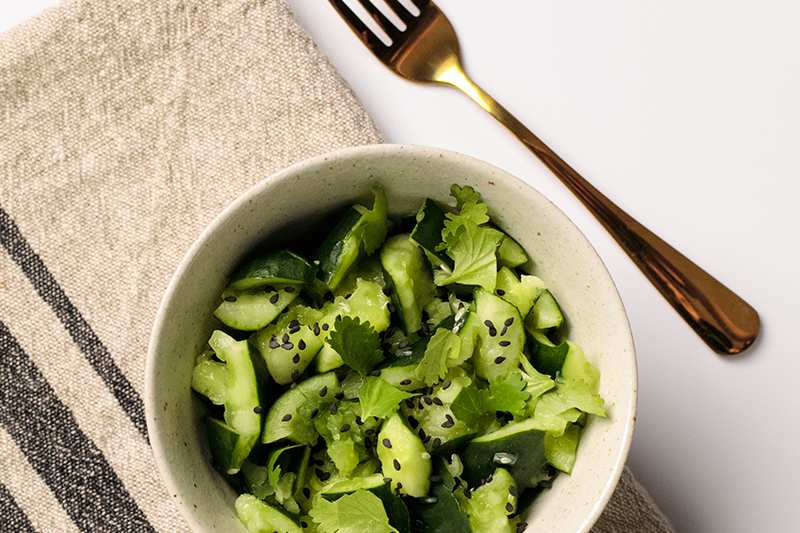 Bowl of smashed cucumbers with napkin and fork