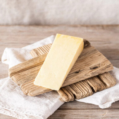 A wedge of Quicke’s mature cheddar on a wooden plank