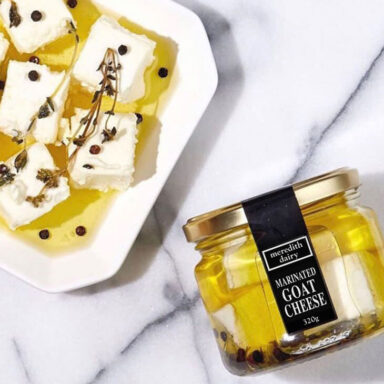 A jar and a plate of Meredith Dairy marinated goat cheese on a marble countertop