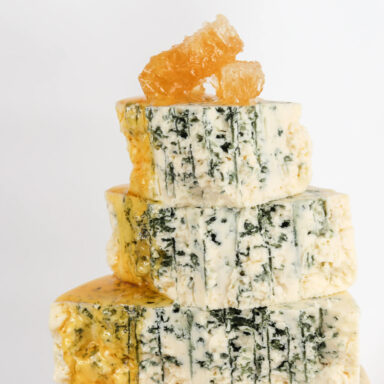 Three squares of Point Reyes Toma cheese with honeycomb on top