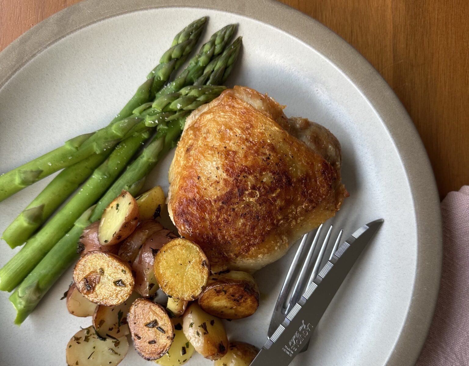 Plate of chicken thighs and spring vegetables.