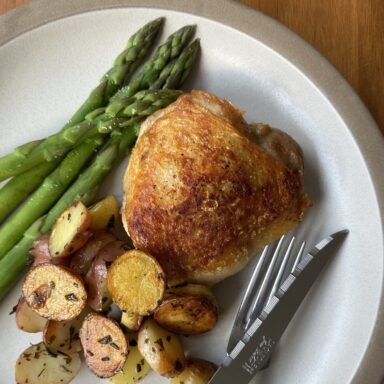 Plate of chicken thighs and spring vegetables.