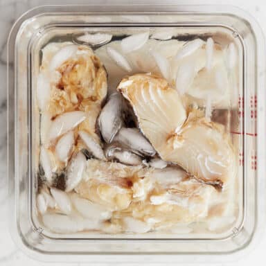 A Clear Plastic Kitchen Tub Filled With Hunks Of Salt Cod Soaking In An Ice Bath