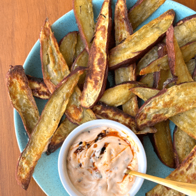 A Big Blue Plate Filled With Golden Sweet Potato Wedges, Including A Small White Ramekin Filled With A Creamy Sauce For Dunking