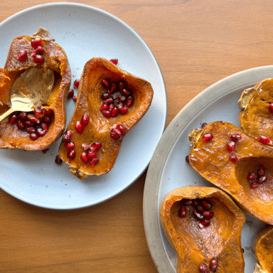 A Platter Full Of Roasted Honeynut Squash Halves Sprinkled With Pomegranate Seeds, With One Squash Pulled Onto An Individual Plate