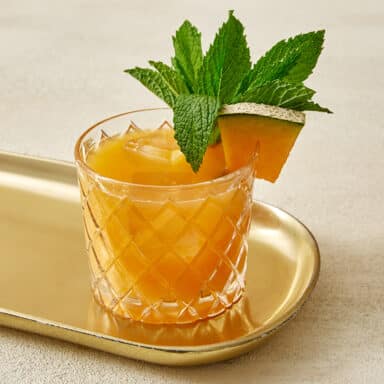 Mezcal cocktail with a mint and melon garnish