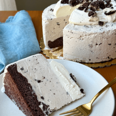 Cookies And Cream Ice Cream Slice On A Plate With Whole Ice Cream Cake In The Background