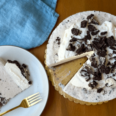 Whole Cookies And Cream Ice Cream Cake Shot From Above With A Slice Taken Out And A Blue Napkin To The Side