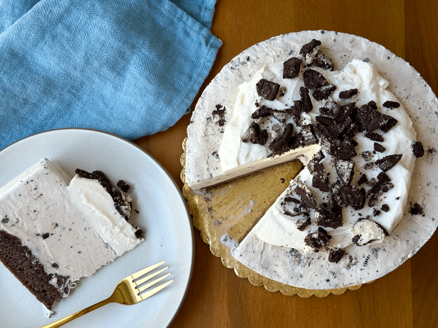 Whole Cookies And Cream Ice Cream Cake Shot From Above With A Slice Taken Out And A Blue Napkin To The Side