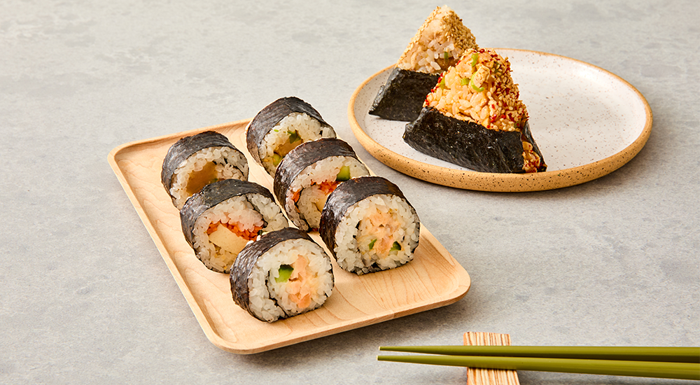 6 Rolls Sushi On Plate Next To 2 Onigiri And Chopsticks On Grey