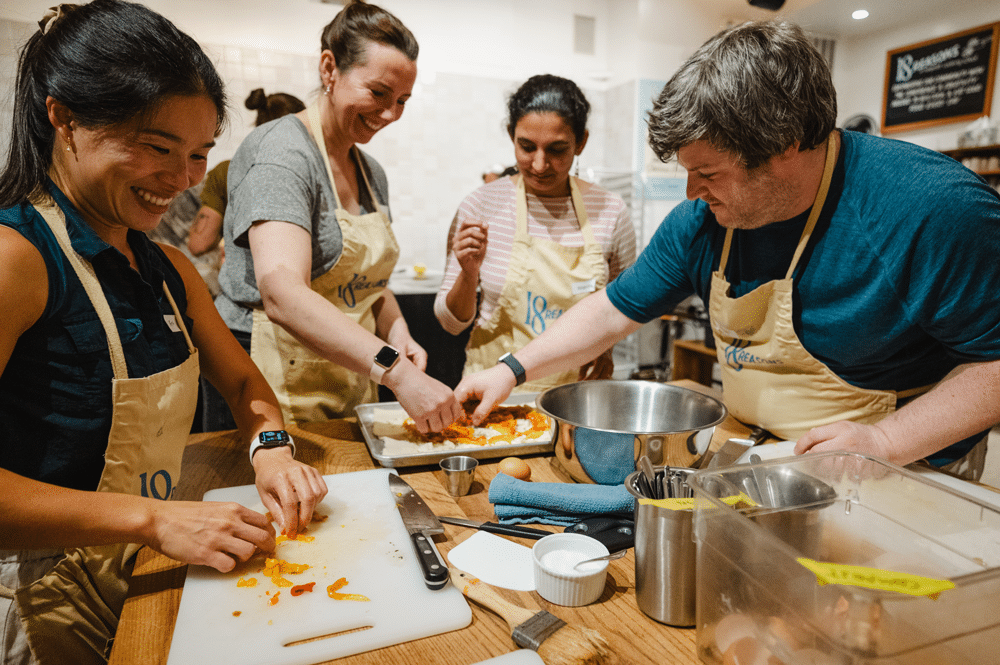 Students smile while prepping bell peppers during an 18 Reasons cooking class