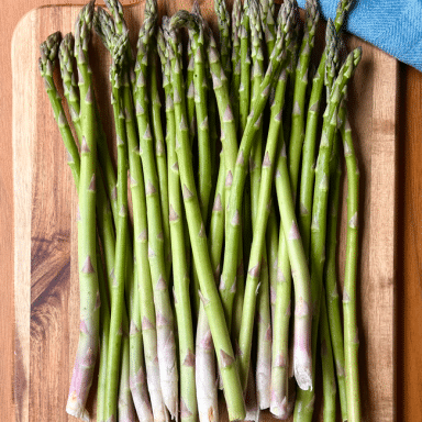 Bunch Of Asparagus On Wood With Blue Napkin Cutting Down Upper Right Side