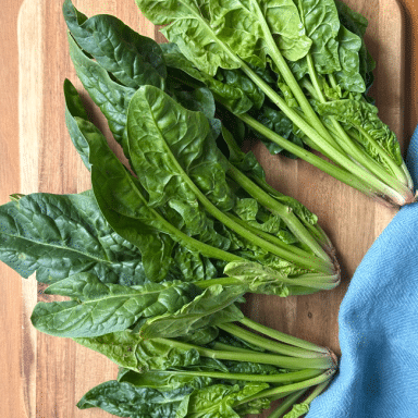 Bunches Of Spinach On Wood With Blue Napkin Cutting Down Right Side