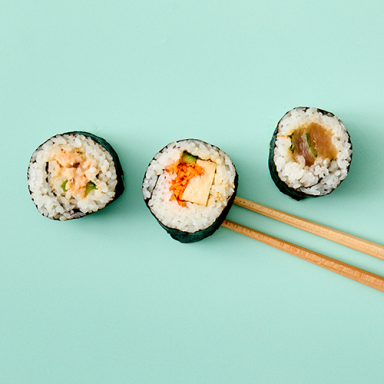 Three Pieces Of Sushi Shot From Above With Chopsticks On Teal Background