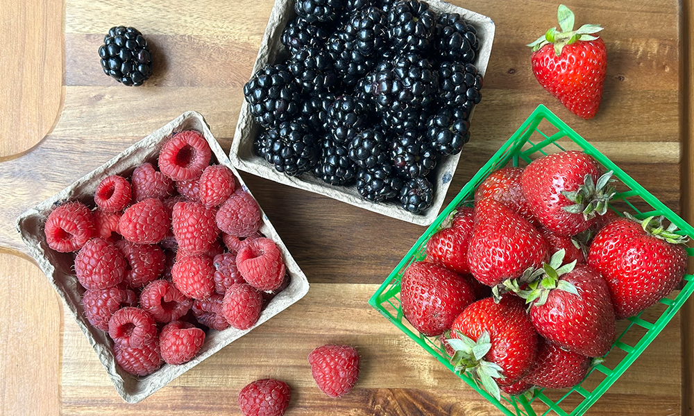 Top Down Shot Of Raspberries Blackberries Strawberries Packaged On Cutting Board